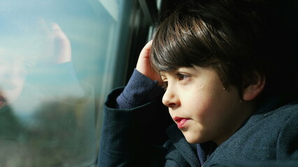 Pensive Child traveling by train looking at scenery pass by, profile close-up face of a 5 year old...