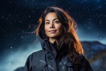 Portrait of a blissful woman in her 30s wearing a functional windbreaker isolated on backdrop of starlit galaxies