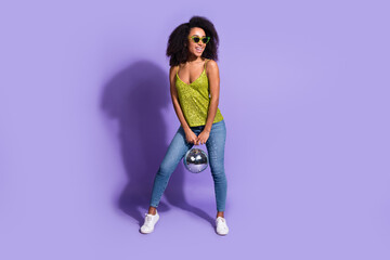 Full length photo of gorgeous young girl sunglass hold discoball wear trendy green sequins outfit isolated on purple color background
