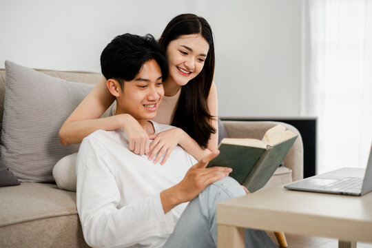 Couple enjoys a peaceful reading session together on a sofa, symbolizing shared interests and a comfortable domestic life.