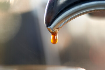 This image elegantly captures the moment of pouring steaming coffee from a metallic pot into a...