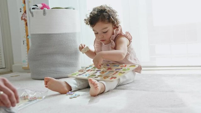 horizontall 4k slow motion video of a little girl with curly hair playing in her room with a wooden alphabet, Montessori material. concept of development and learning in the childhood