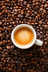 Fototapeta premium Freshly Brewed Coffee in a Black Cup Surrounded by Coffee Beans