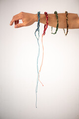 Arm stretched out on a white background with different handmade thread necklaces.