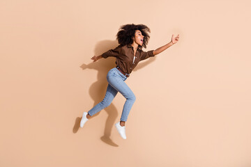 Fototapeta na wymiar Full size photo of mixed race multiethnic multinationa woman dressed brown shirt run to empty space isolated on beige color background