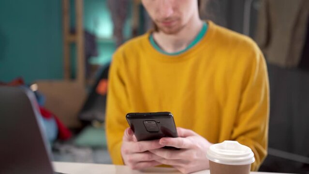 man stares in smartphone screen rects to news feels lazy surrounded garbage in messy room