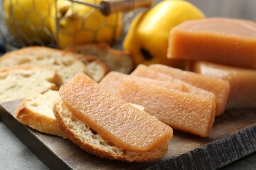 Fototapeta na wymiar Tasty sweet quince paste, bread and fresh fruits on grey table, closeup