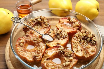 Tasty baked quinces with walnuts and honey in bowl on table, closeup
