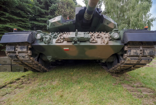 Polska Kalków 27 sierpnia 2023 o 11:11. Czołg Leopard na festynie wojskowym. Czołg z polską flagą na opancerzeniu widziany od przodu wśród drzew.