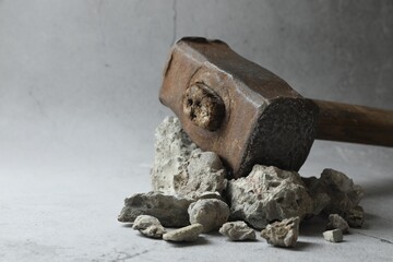 One sledgehammer and pieces of broken stones on grey background, closeup. Space for text