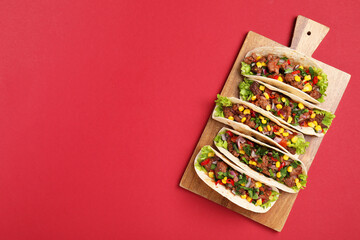 Delicious tacos with meat and vegetables on red table, top view. Space for text
