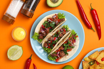 Flat lay composition with delicious tacos on orange table