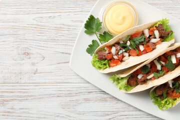 Delicious tacos with meat and vegetables served on wooden table, top view. Space for text
