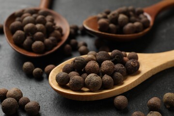 Dry allspice berries (Jamaica pepper) on black table, closeup