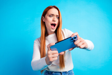 Photo portrait of attractive young woman play mobile game have fun dressed stylish white clothes isolated on blue color background