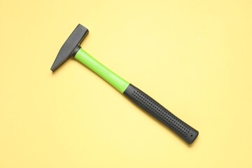 New hammer with rubber handle on yellow background, top view