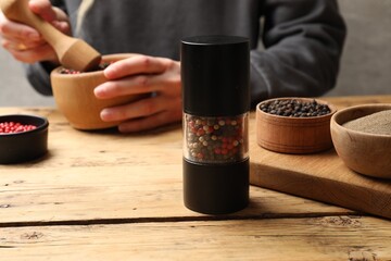 Ground pepper and grains on wooden table, selective focus. Space for text