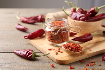 Chili pepper flakes and pods on wooden table