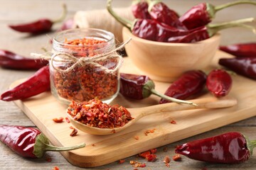Chili pepper flakes and pods on wooden table