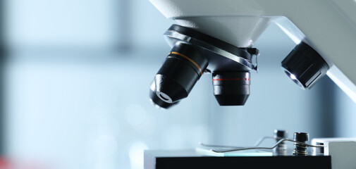 Microscope with glass slide on blurred background, closeup. Space for text