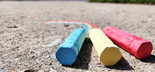 Chalk colors forming a rainbow pattern on the driveway pavement. Blue, yellow and red chalk representing hobbies and recreation.