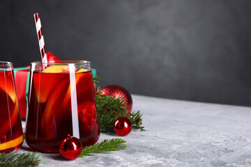 Delicious Sangria drink in glasses and Christmas decorations on grey textured table, closeup. Space...