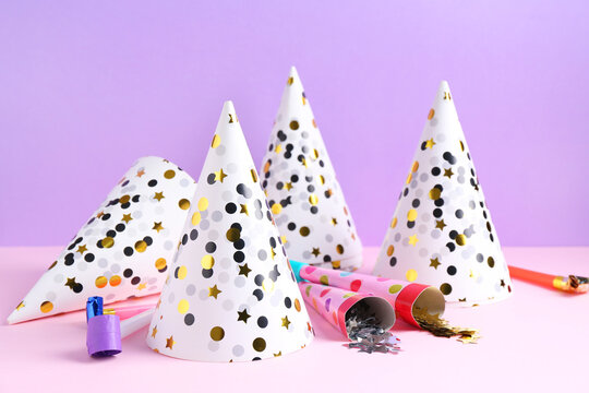 Party hats, confetti and blowers on color background