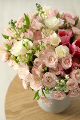 Beautiful bouquet of fresh flowers in vase on wooden table