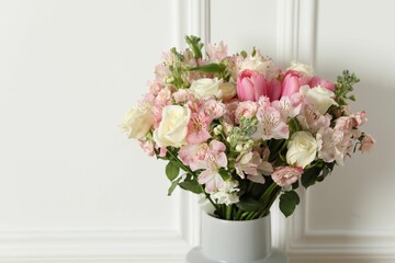Beautiful bouquet of fresh flowers in vase near white wall, space for text