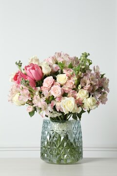 Beautiful bouquet of fresh flowers in vase on table near white wall