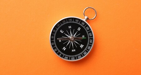 One compass on orange background, top view