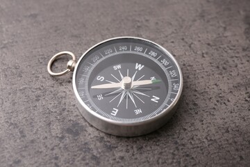 Fototapeta na wymiar One compass on grey table, closeup. Tourist equipment