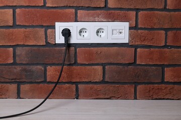 Power sockets and electric plug on brick wall