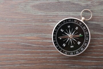 One compass on wooden table, top view. Space for text