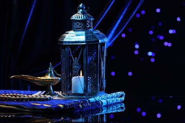 Arabic lantern, misbaha, Aladdin magic lamp and folded prayer mat on mirror surface against blurred...