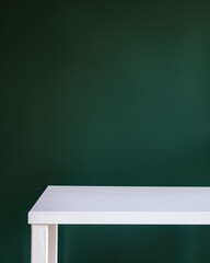 Closeup photo of clean white table with dark green room in background.