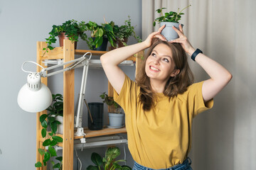 Young woman watering indoor plants in her house. Beautiful young woman taking care of house flowers...