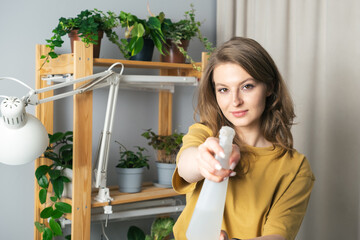 Young woman watering indoor plants in her house. Beautiful young woman taking care of house flowers in her flat. Jungle concept in her home.