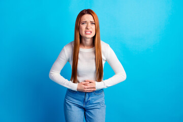 Photo portrait of attractive young woman touch stomach suffer ache dressed stylish white clothes isolated on blue color background