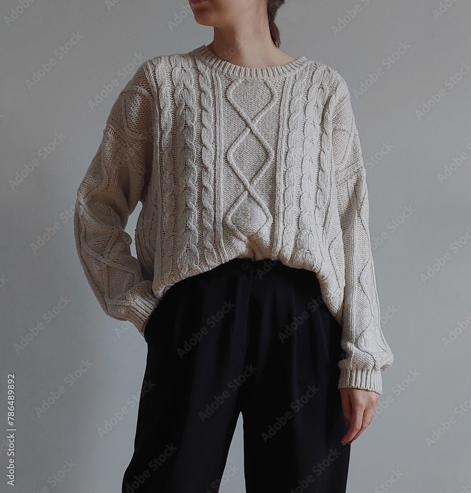 Wall mural Young woman wearing cream sweater with black pants isolated on light background. - Wall murals