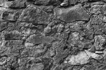 in the photo there is an old gray stone wall close up