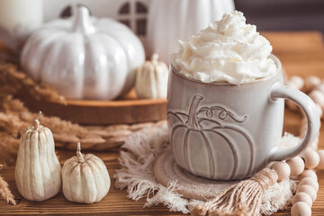 A seasonal drink. Delicious pumpkin latte with whipped cream and cinnamon in a mug on a wooden...