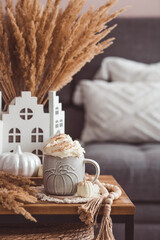 A seasonal drink. Delicious pumpkin latte with whipped cream and cinnamon in a mug on a wooden...
