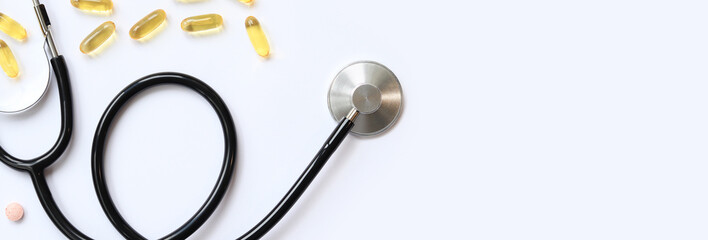 Stethoscope and vitamins on a white background, top view. Medical instrument and various medicines,...