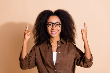 Portrait of nice woman with wavy hair dressed brown shirt in eyewear indicating at discount empty...