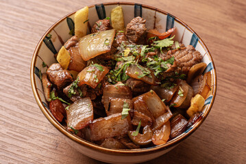 carne en salsa con cebolla, con papas fritas.