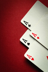 A winning playing card combination of four aces in poker or four of a kind or quads. Concept of luck or fortune in casino game on red table. Space for advertising