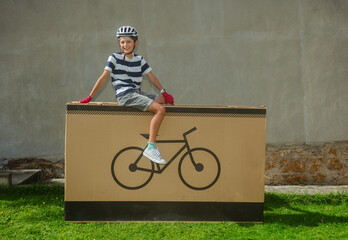 Grinning teenager cyclist posing on large bike-icon package - obrazy, fototapety, plakaty