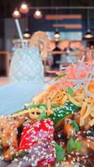 Close-up chicken wok bokeh. Restaurant interior background. Romantic dinner in cozy cafe. Asian cuisine. Delicious food and drinks. Bowl dish of chopped vegetables and noodles topped with sesame seeds