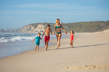Family enjoy leisure run along sandy shoreline with waves crash